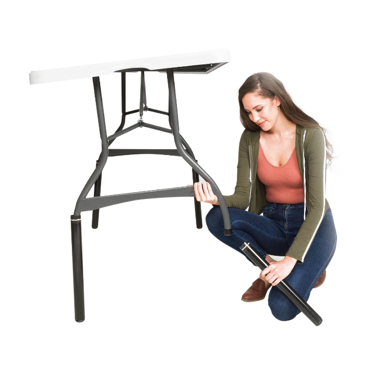 A person adjusting a folding table riser under a white folding table, which is placed on a plain background.